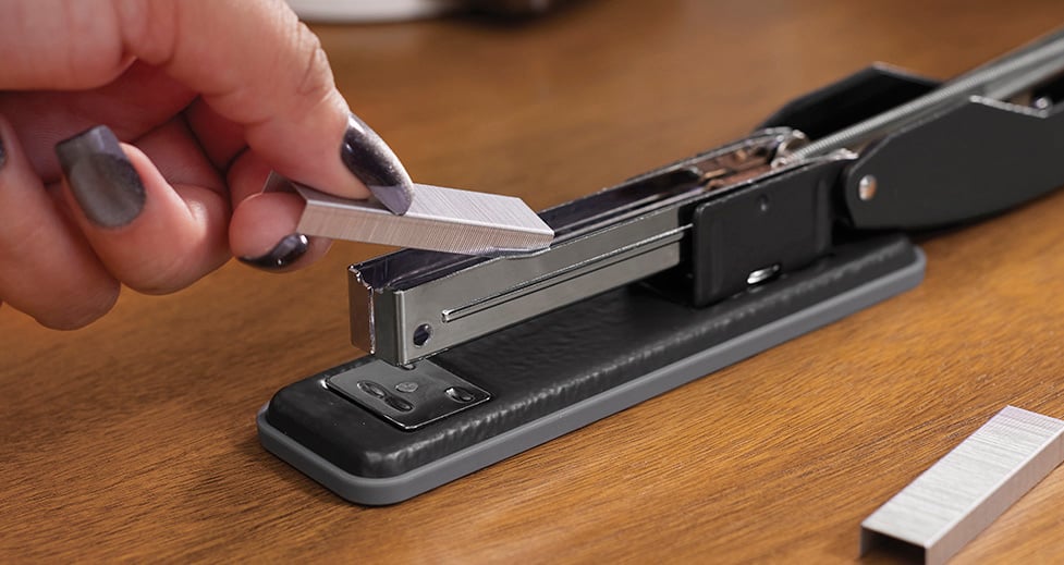 Close up view of a woman loading staples into a top-loading stapler. Close up view of a woman loading staples into a top-loading stapler.