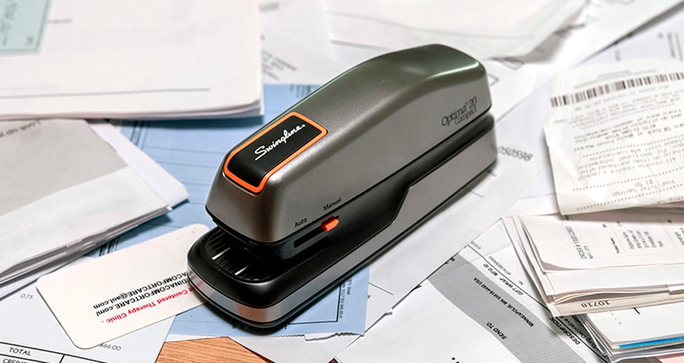 The Optima 20 Stapler on a desk surrounded by receipts and tax documents. The Optima 20 Stapler on a desk surrounded by receipts and tax documents.