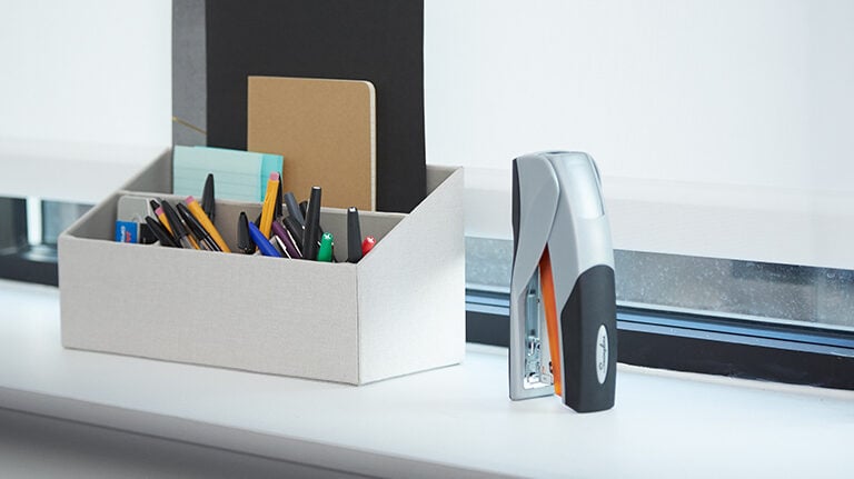 Swingline stapler next to a bin of desk supplies