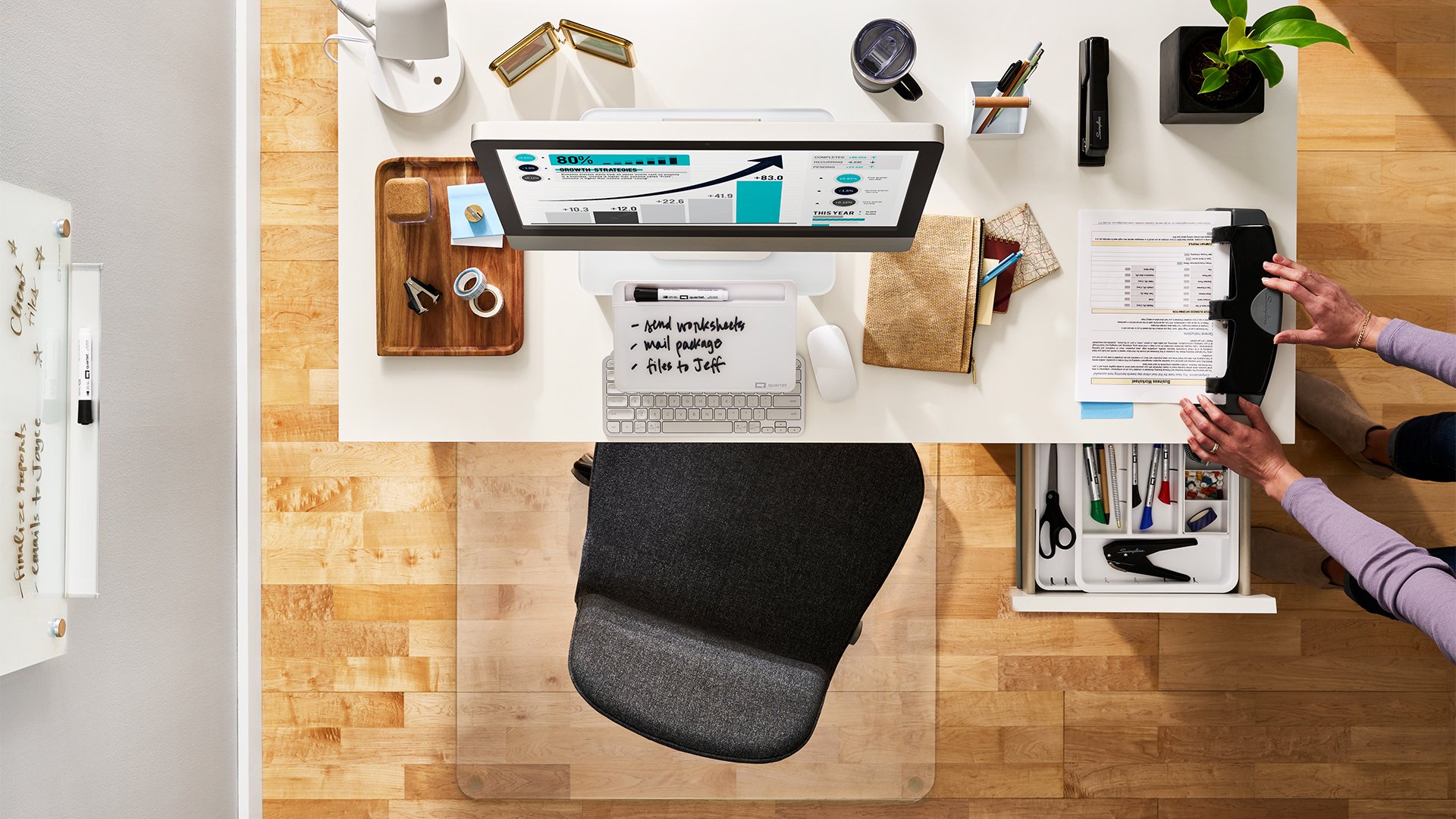 mAssorted Swingline products on a desk with a woman using a 3-hole punch