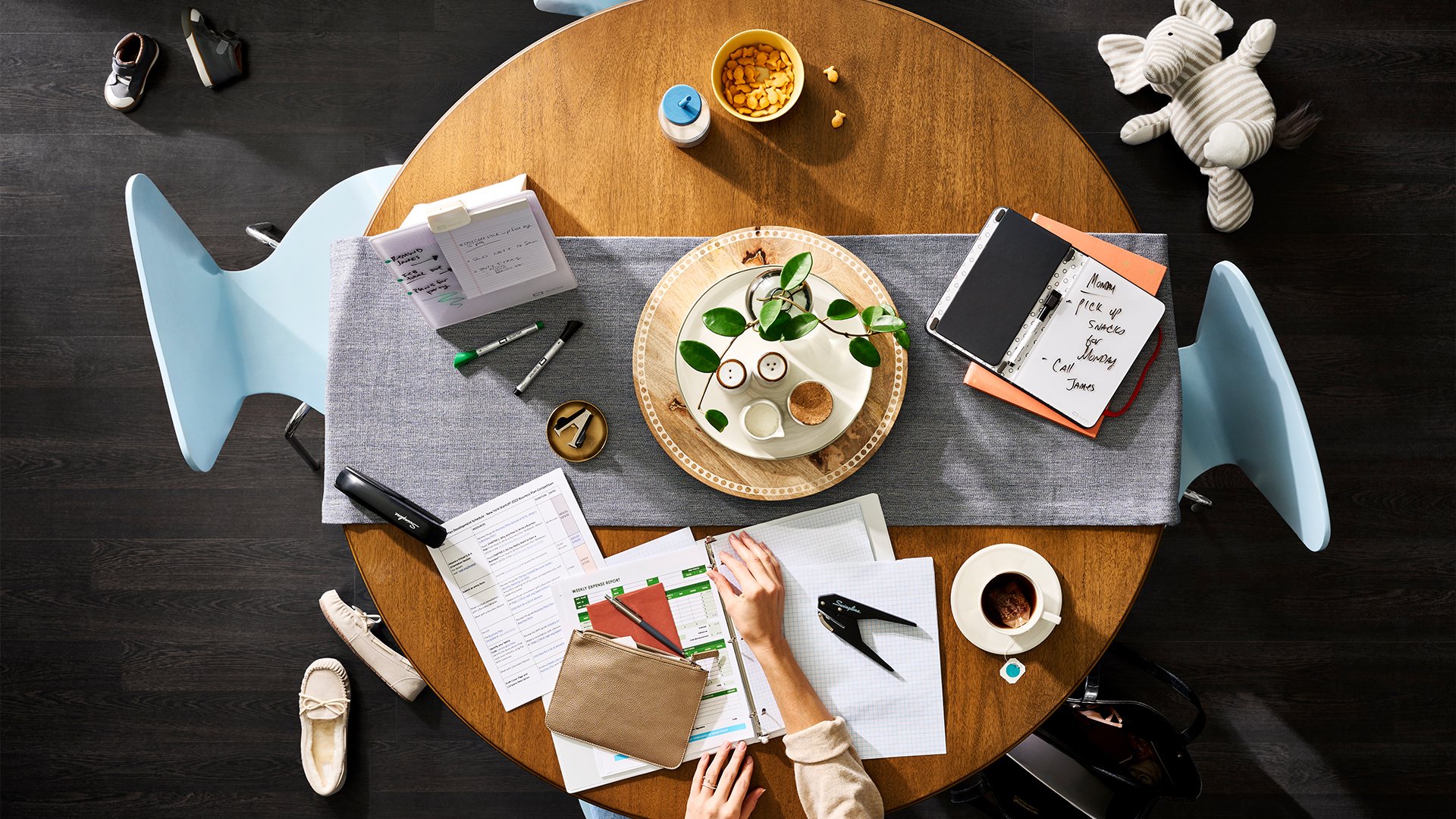 A woman sitting at a kitchen table with assorted Swingline products throughout it.